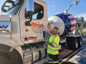 A man and his daughter stand beside a Bleigh Ready Mix truck.